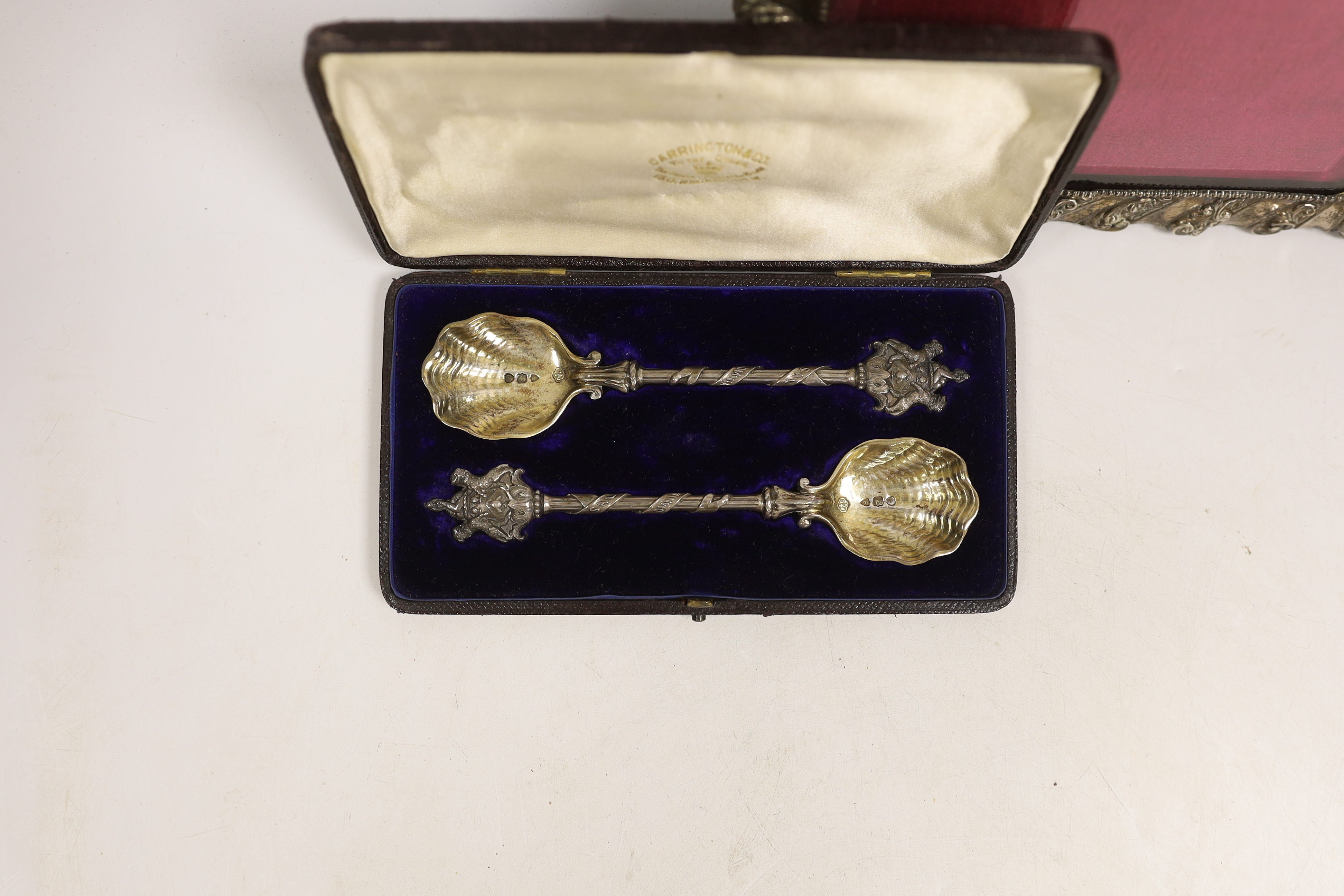 A Victorian cased pair of silver spoons with armorial terminals, Carrington & Co, London, 1903, 18.6cm, together with a late Victorian silver mounted photograph frame, Henry Matthews, Birmingham, 1899, width 24.3cm.